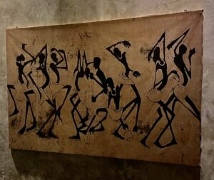African wall art showing stylized dancing figures on natural fabric background.
