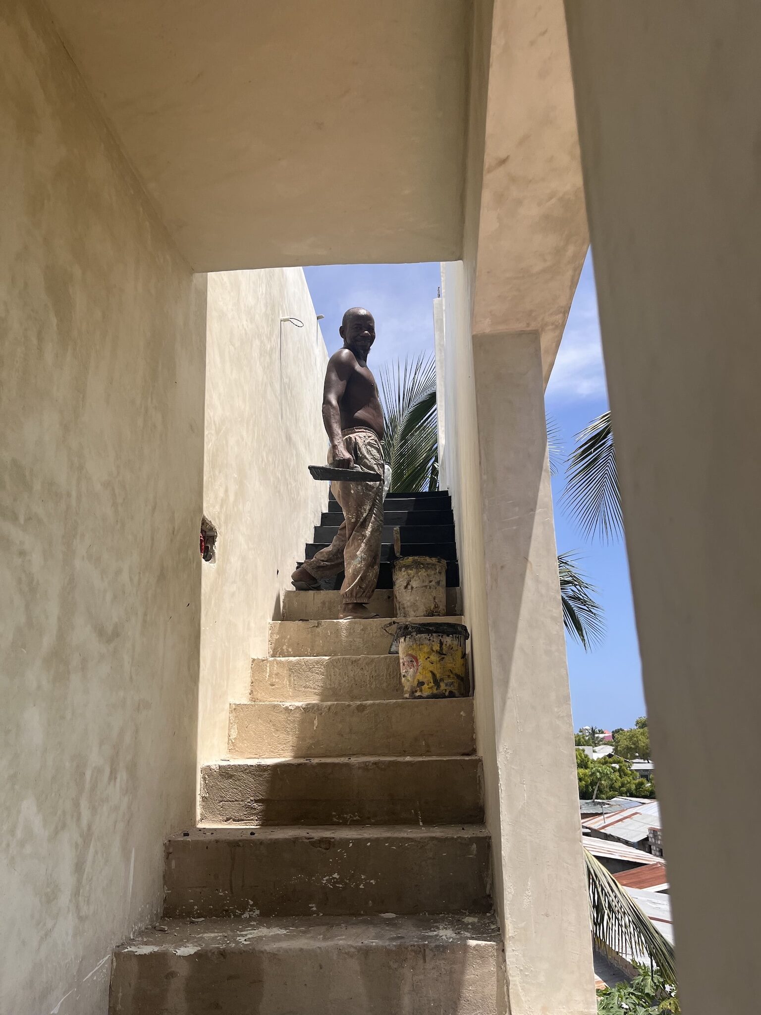 Local craftsman standing on concrete stairs during construction work in Zanzibar.