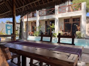 View from a wooden dining table across the courtyard pool at a Zanzibar bungalow.