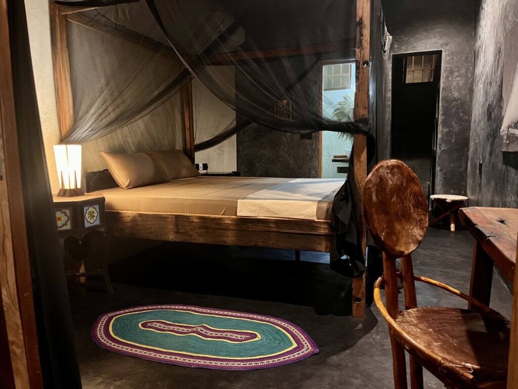Interior bedroom view in Zanzibar with mosquito net and wooden furniture.
