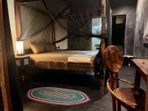 Interior bedroom view in Zanzibar with mosquito net and wooden furniture.