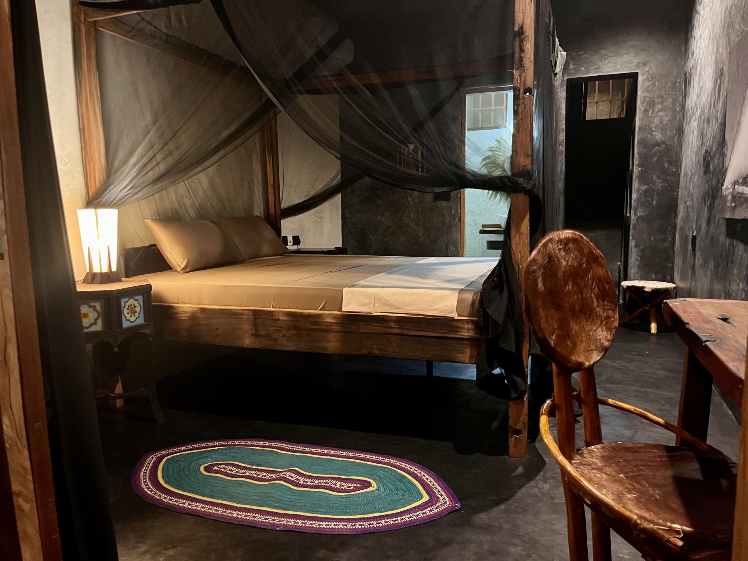 Interior bedroom view in Zanzibar with mosquito net and wooden furniture.