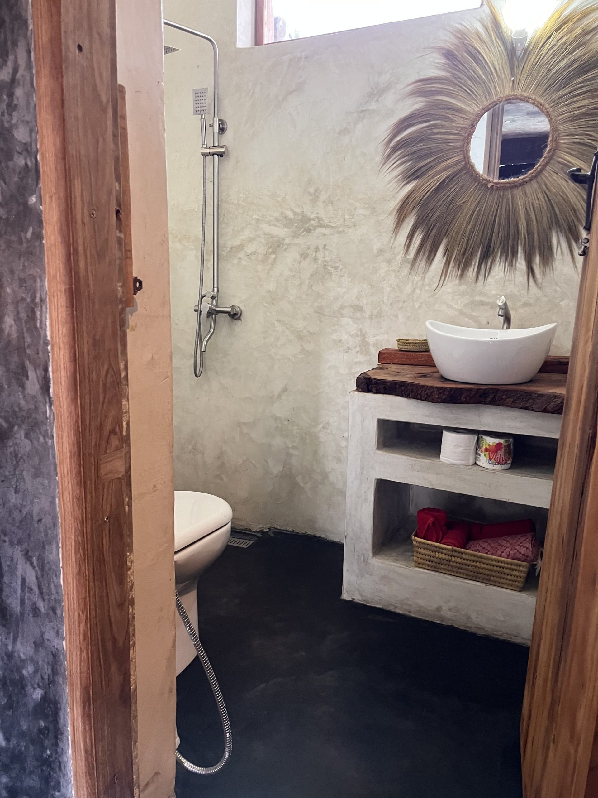Modern bathroom inside a Zanzibar bungalow with walk-in shower and natural stone walls.
