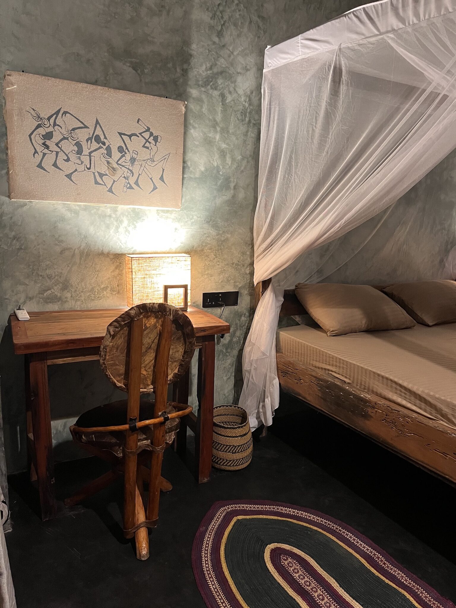 Bedroom in Zanzibar bungalow with mosquito net, wooden furniture and warm ambient lighting.