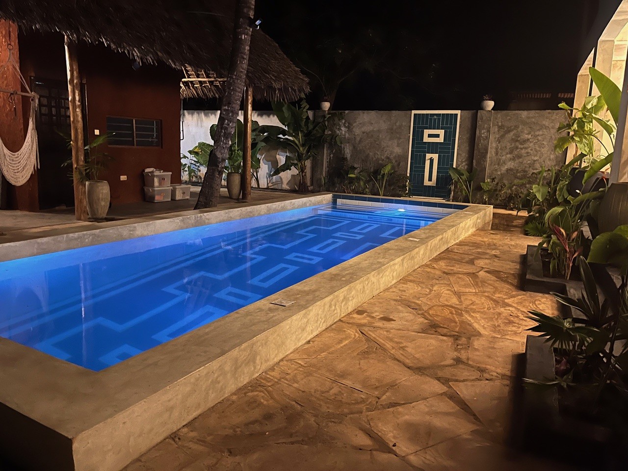 Illuminated private pool at night in a Zanzibar bungalow courtyard.
