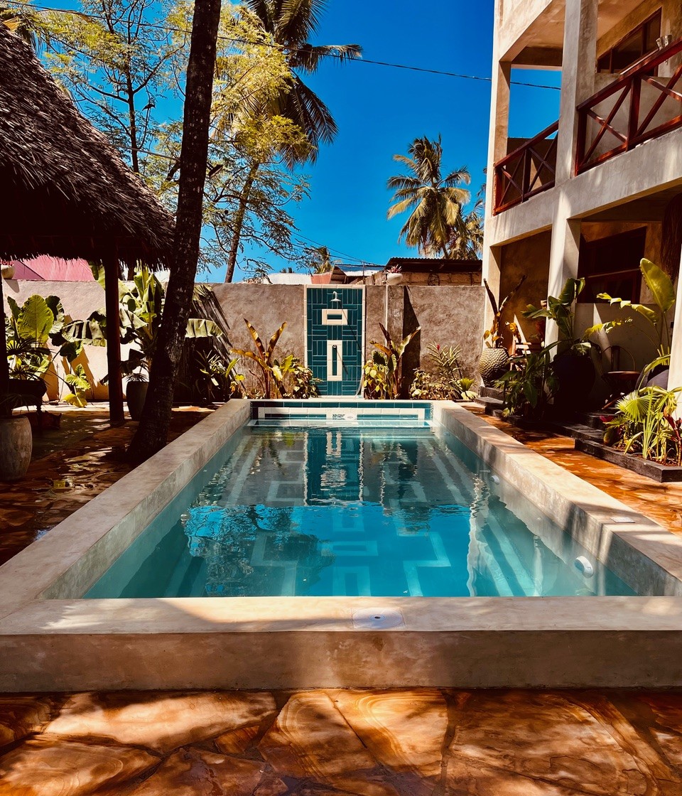 Front view of a private swimming pool in a Zanzibar bungalow under blue sky.