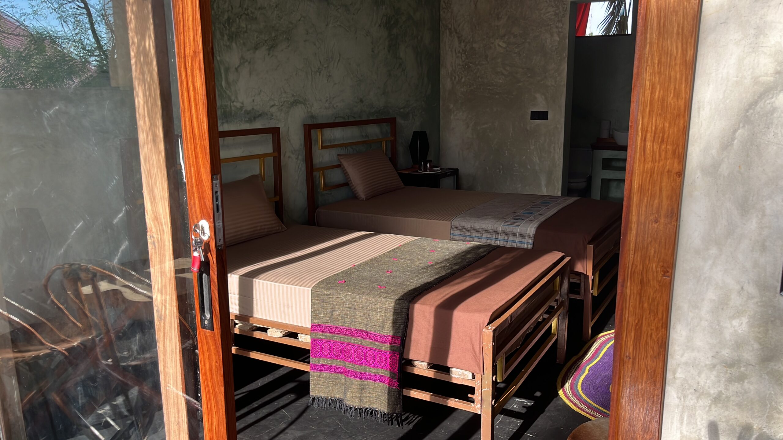 Twin bedroom inside a Zanzibar bungalow with two single beds and natural wooden interior.